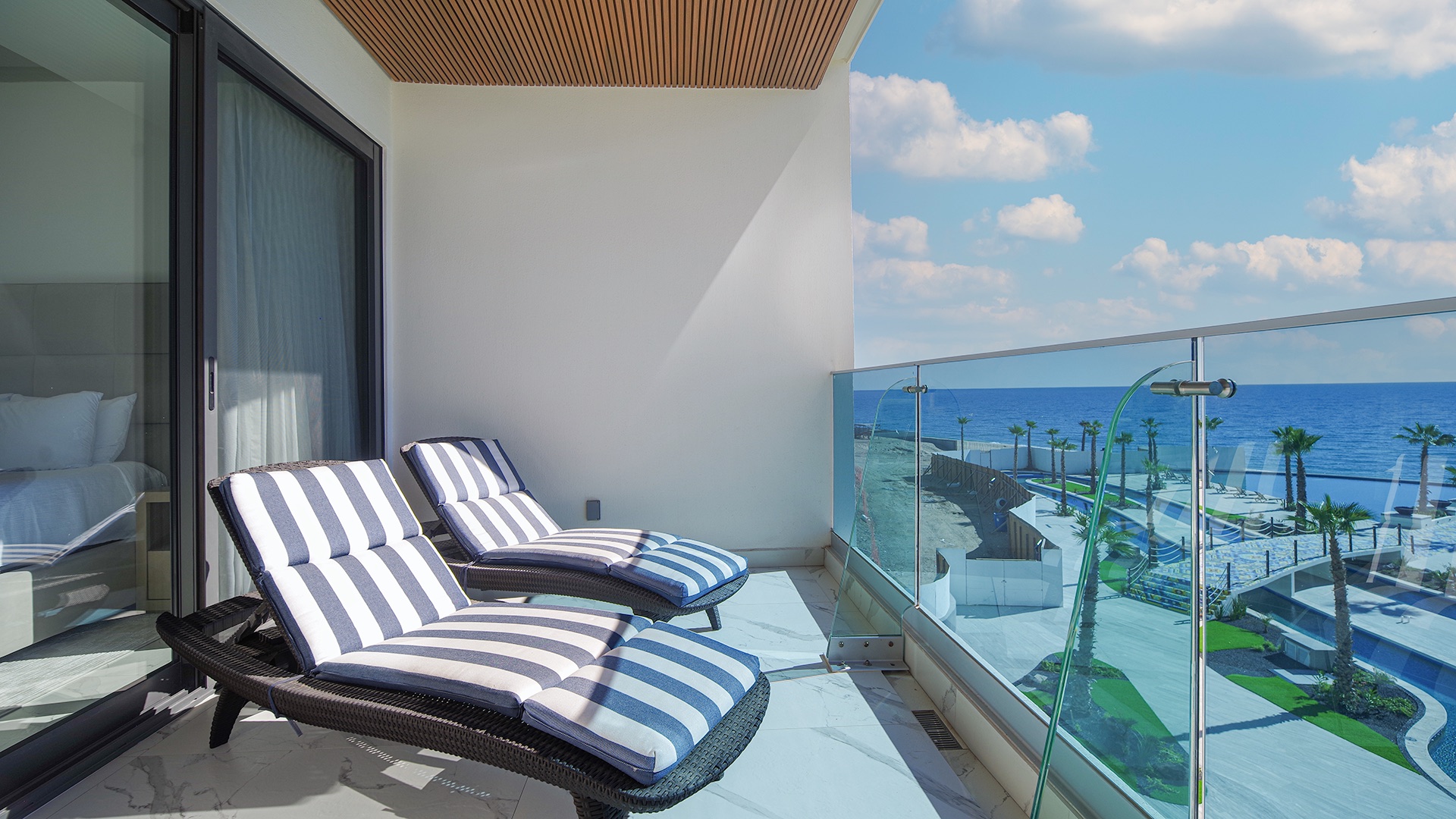 Private balcony with two loungers overlooking the pools and the Sea of Cortez at Encantame Soleil